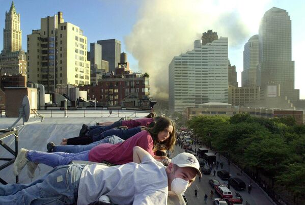 James Bahn, foreground, and Irena Musial watch from a building rooftop on Greenwich St. in New York on Wednesday, 12 September 2001 as the street below is filled with rescue workers and equipment.  - Sputnik International