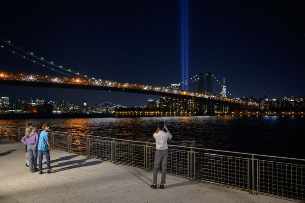 People take photos from the Brooklyn waterfront of a light installation entitled &quot;Tribute in Light&quot; commemorating the 9/11 terrorist attacks, in New York on 10 September 2021. - Sputnik International