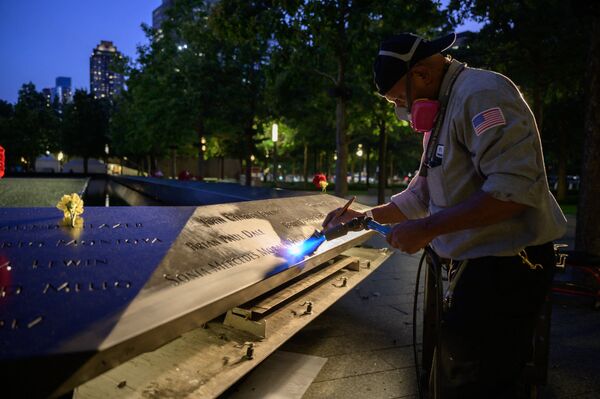 A worker cleans a display showing the names of the lives lost in the 9/11 terrorist attacks before a reflecting pool at the 9/11 memorial in New York on 10 September 2021. - Sputnik International