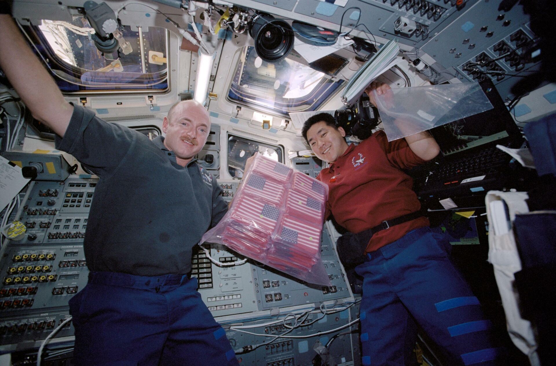 STS-108 astronauts Mark Kelly, left, and Dan Tani hold commemorative American flags the shuttle Endeavour in December 2001. - Sputnik International, 1920, 11.09.2021