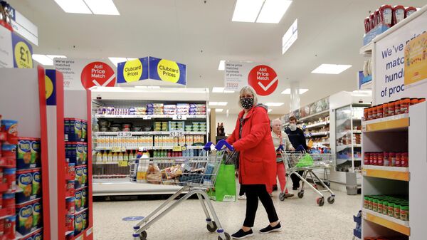 A woman wearing a face mask pushes a shopping cart at a British supermarket - Sputnik International