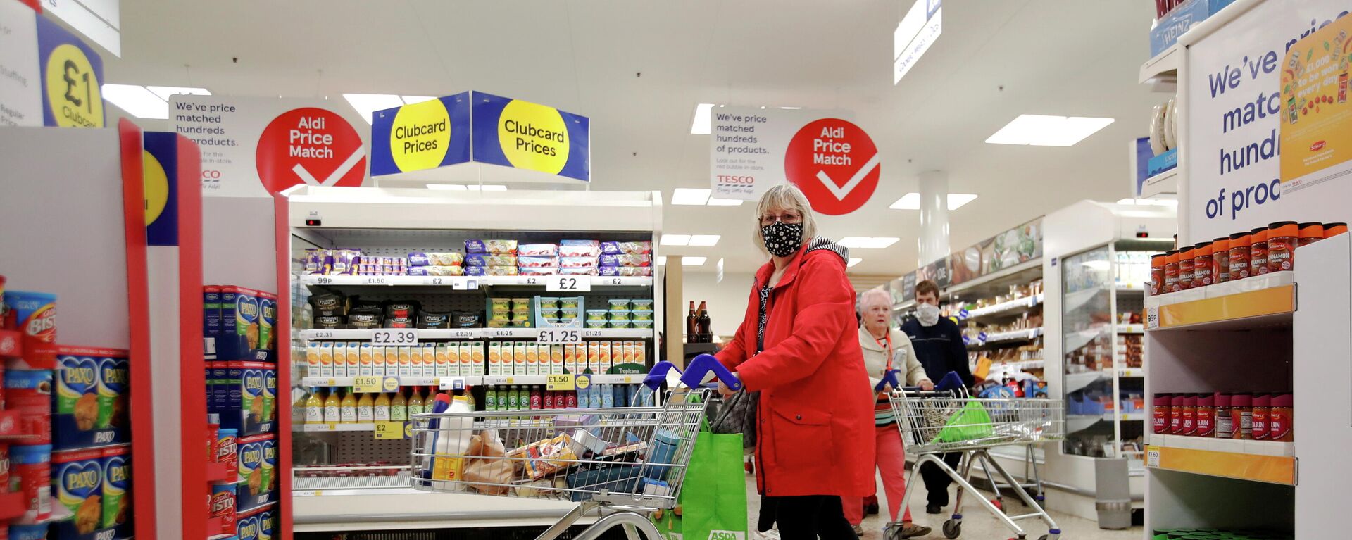 A woman wearing a face mask pushes a shopping cart at a British supermarket - Sputnik International, 1920, 15.09.2021