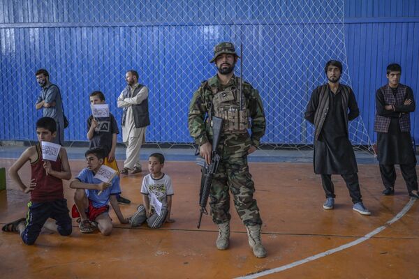 A Taliban fighter stands as youths wait to show their skills during an event organised for the visit of the Taliban&#x27;s director of physical education and sports, Bashir Ahmad Rustamzai (not pictured), at a gymnasium in Kabul on 14 September 2021. - Sputnik International