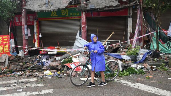 A person pushes a bicycle past damaged buildings, following an earthquake in Luzhou city of the southwestern province of Sichuan, China on 16 September 2021.  - Sputnik International