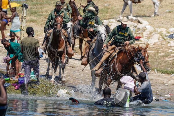 United States Border Patrol agents on horseback attempt to stop Haitian migrants from entering an encampment on the banks of the Rio Grande near the Acuna Del Rio International Bridge in Del Rio, Texas on 19 September 2021.  - Sputnik International