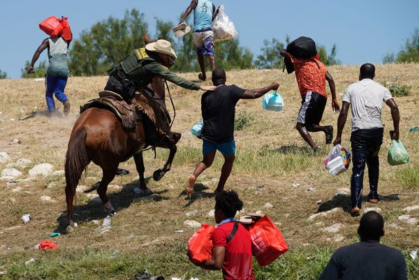 A United States Border Patrol agent on horseback tries to stop a Haitian migrant from entering an encampment on the banks of the Rio Grande near the Acuna Del Rio International Bridge in Del Rio, Texas on 19 September 2021. - Sputnik International