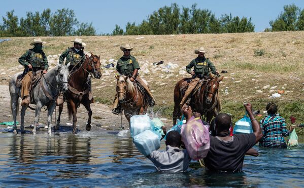 United States Border Patrol agents on horseback try to stop Haitian migrants from entering an encampment on the banks of the Rio Grande near the Acuna Del Rio International Bridge in Del Rio, Texas on 19 September 2021.  - Sputnik International