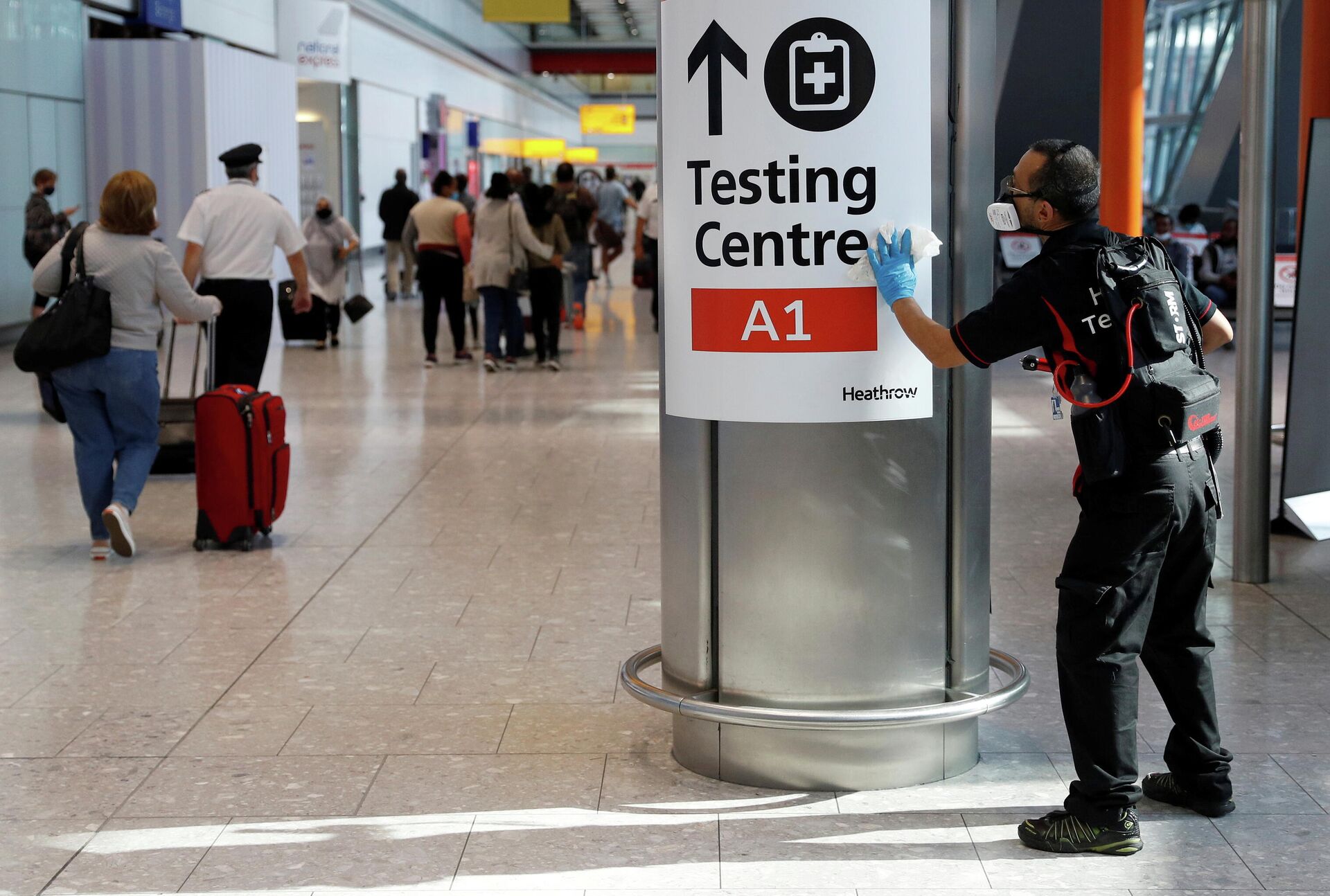 A worker sanitises a sign at the International arrivals area of Terminal 5 in London's  Heathrow Airport, Britain, August 2, 2021 - Sputnik International, 1920, 15.10.2021