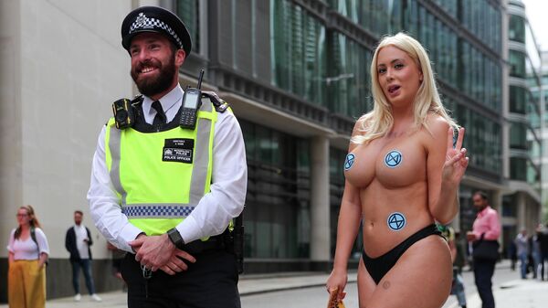 An Extinction Rebellion climate activist poses next to a police officer during a protest, in London, Britain August 27, 2021.  - Sputnik International