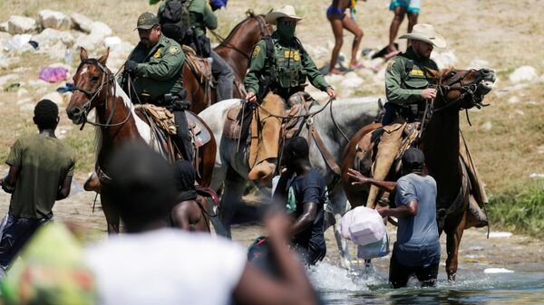 U.S. law enforcement officers on horseback block the way to migrants reaching the shores of the Rio Grande as they try to return to the United States after buying food in Mexico, as seen from Ciudad Acuna, Mexico September 19, 2021. Picture taken September 19, 2021 - Sputnik International