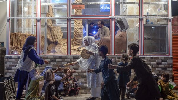 Женщина раздает хлеб нуждающимся детям перед пекарней в Кабуле - Sputnik International