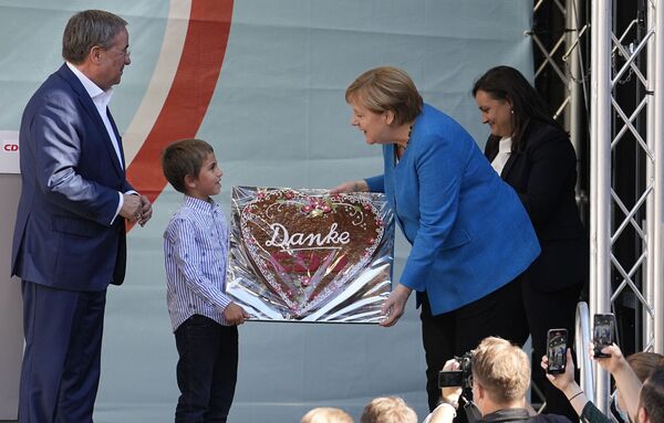 Chancellor Angela Merkel gets a traditional gingerbread reading Thanks CDU beside Governor Armin Laschet, top candidate for the upcoming election, left, at the final election campaign event of the Christian Democratic Party, CDU, ahead of the German general election in Aachen, Germany, Saturday, 25 September 2021.  - Sputnik International