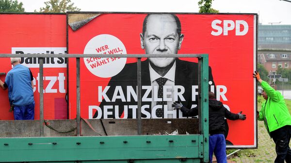 Workers remove an election campaign poster showing Social Democratic Party (SPD) top candidate for chancellor Olaf Scholz, the day after the German general elections, in Bad Segeberg near Hamburg, Germany, September 27, 2021. - Sputnik International
