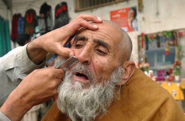 An Afghan barber shaves the moustache of an elderly man in Jalalabad, the provincial capital of Nangarhar province, east of Kabul on 20 December 2006. - Sputnik International