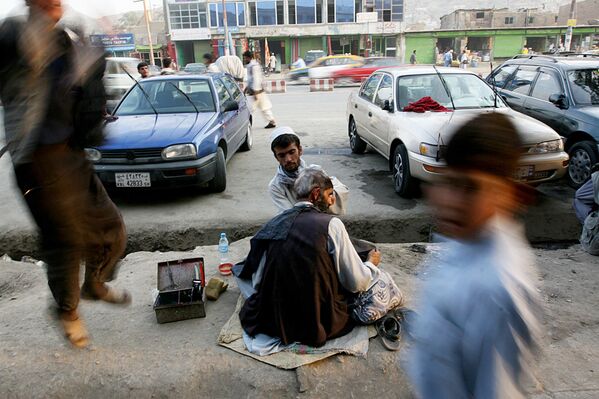 An Afghan barber cuts a man&#x27;s hair as people walk by in Kabul, 17 September 2007. - Sputnik International