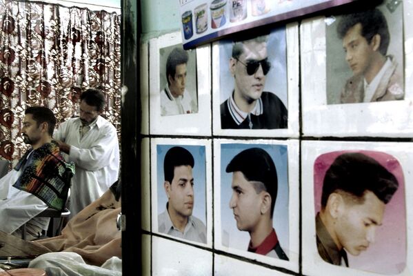 A man gets a haircut in a barbershop in Kabul, 19 June 2002 as pictures depicting different haircut styles – all without beard – are displayed on the wall. Since the end of the last Taliban era, an increasing number of Afghan men have abandoned the long beard, which was imposed during the fundamentalist Islamic regime. - Sputnik International