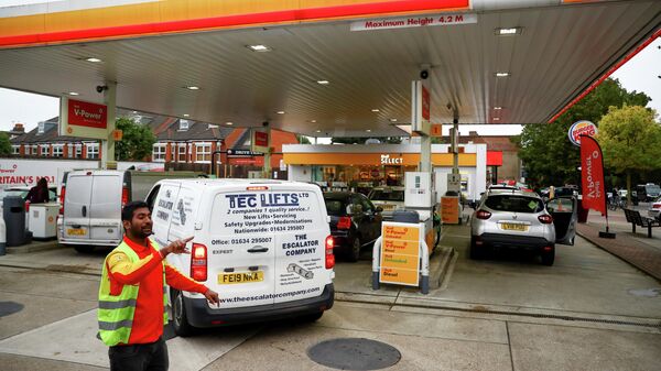 A worker guides vehicles into the forecourt as they queue to refill at a fuel station in London - Sputnik International