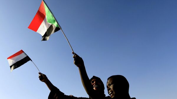 Sudanese wave their national flag as they gather at freedom square during the first anniversary of the start of the uprising that toppled long-time ruler Omar al-Bashir, in Khartoum, Sudan December 19, 2019.  - Sputnik International