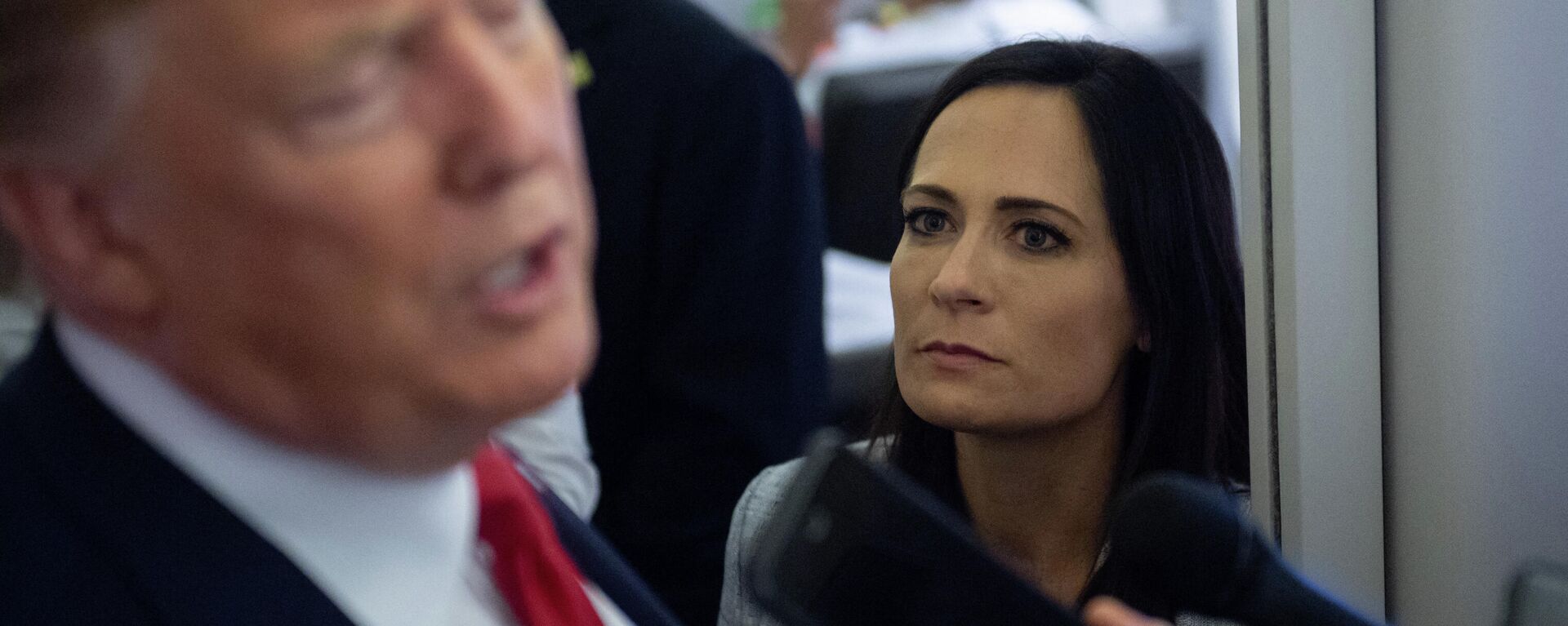 In this file photo former White House Press Secretary Stephanie Grisham listens as US President Donald Trump speaks to the media aboard Air Force One while flying between El Paso, Texas and Joint Base Andrews in Maryland, August 7, 2019. - An aide dubbed the Music Man was tasked with playing calming tunes for Donald Trump when he went into rages, according to a scandal-filled book by a former press secretary.Stephanie Grisham, notorious for not giving a single televised press conference while serving as Trump's chief spokeswoman, writes in I'll Take Your Questions Now that her boss went into terrifying rants.The former president and his wife Melania have vociferously condemned the book, excerpts of which appeared on September 28, 2021 in The New York Times and Washington Post. - Sputnik International, 1920, 04.10.2021