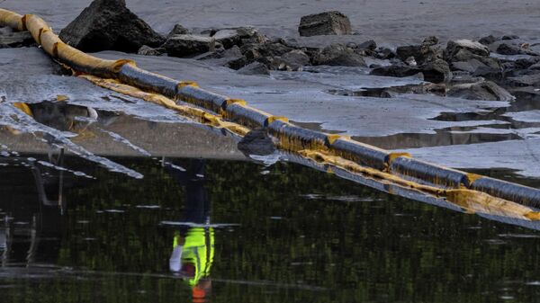 A worker is reflected in the water of an estuary after a major oil spill off the coast of California came ashore in Huntington Beach, California, U.S., October 4, 2021. - Sputnik International