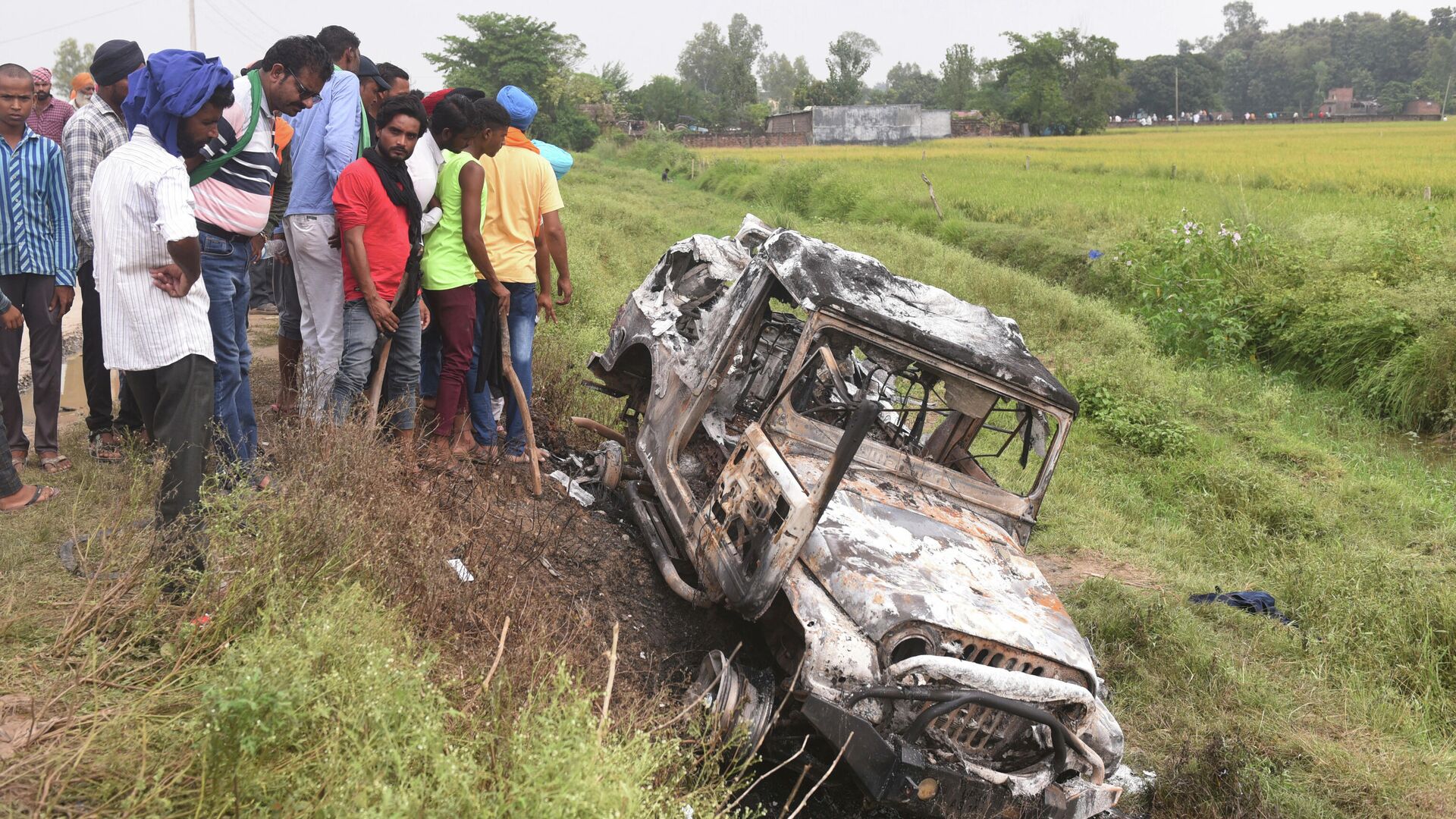 Villagers watch a burnt car which run over and killed farmers on Sunday, at Tikonia village in Lakhimpur Kheri, Uttar Pradesh state, India, Monday, Oct. 4, 2021 - Sputnik International, 1920, 07.10.2021