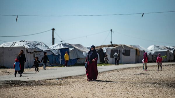 Women with children walk at Camp Roj, where relatives of people suspected of belonging to the Islamic State (IS) group are held, in the countryside near al-Malikiyah (Derik) in Syria's northeastern Hasakah province, on March 28, 2021. - Sputnik International