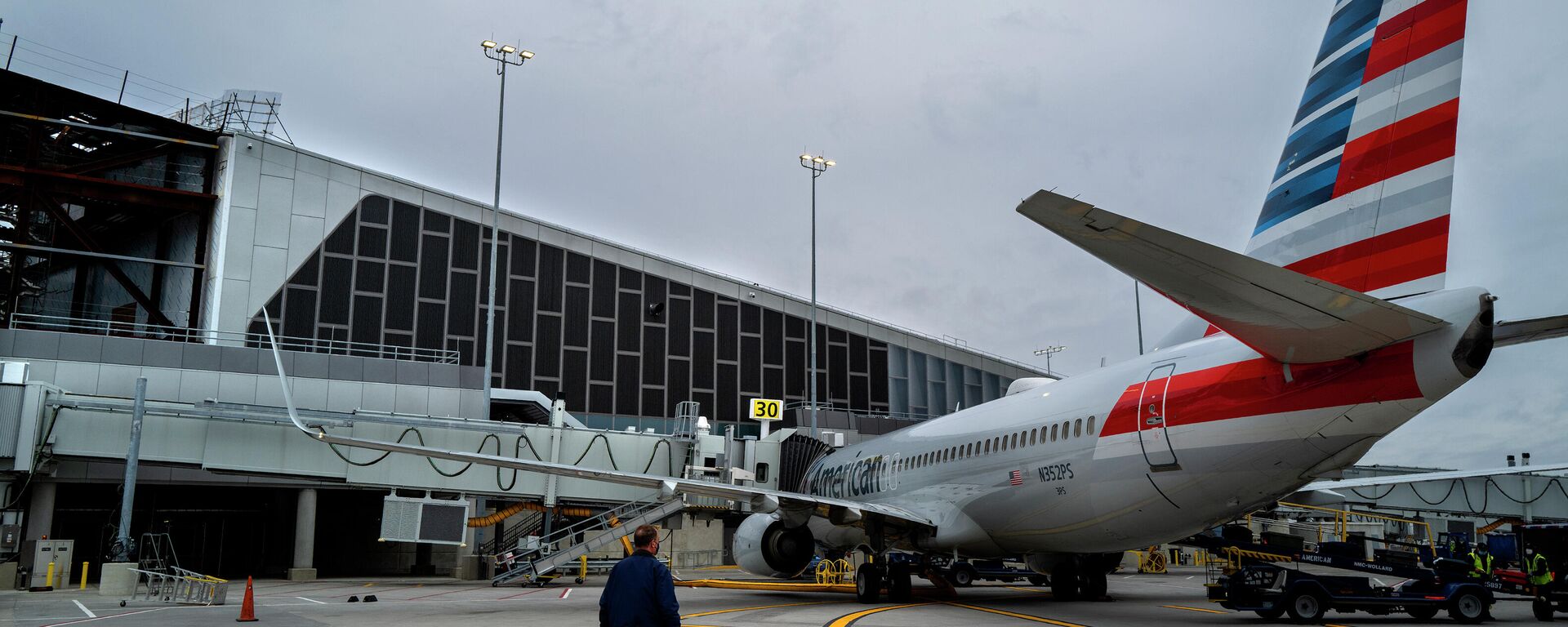 Christopher Rhoads, Manager of Airport Operations/Aviation at LaGuardia Airport in New York, stands near an American Airlines passenger jet being served at gate 30, Wednesday, March 24, 2021, near newer construction at the airport, part of a multi-year, multi-billion dollar project that will modernize almost the entirety of the airport's departure and arrival terminals. - Sputnik International, 1920, 09.10.2021