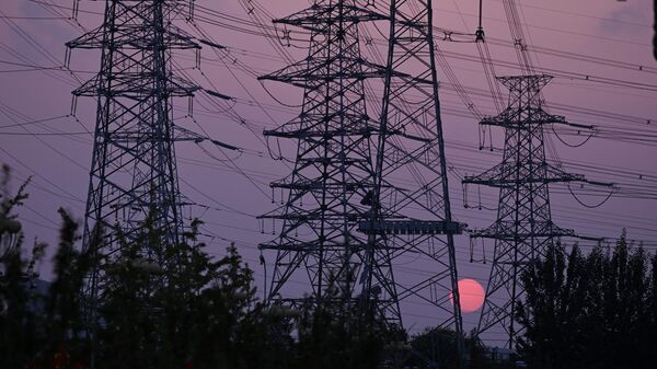 The sun sets behind electricity power pylons in Beijing on September 28, 2021 - Sputnik International