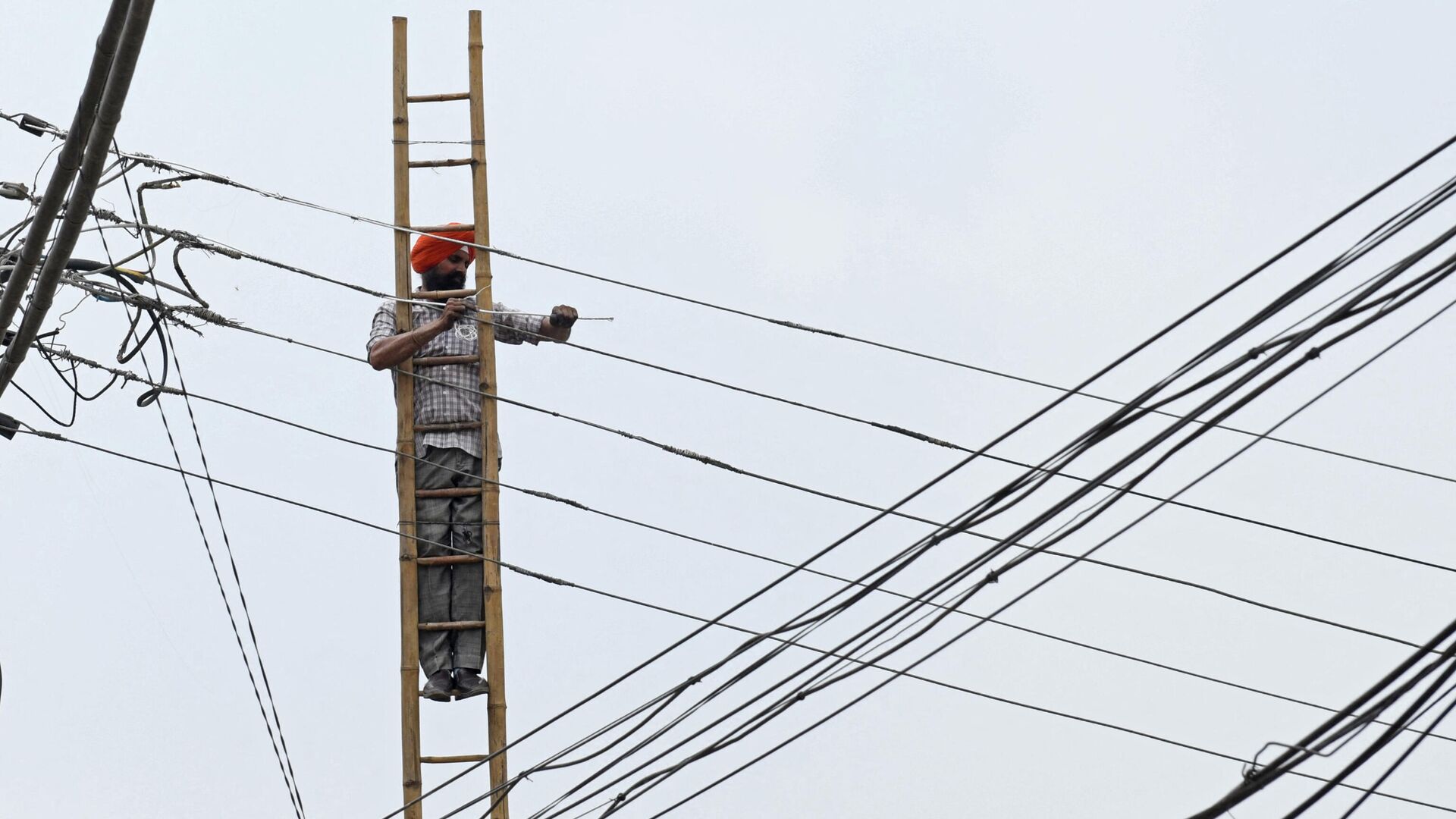 An employee of the Indian Punjab State Power Corporation Ltd, works on overhead electric cables in Amritsar on July 10, 2021 - Sputnik International, 1920, 11.10.2021