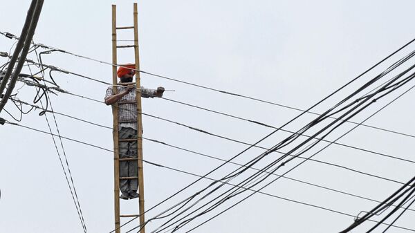 An employee of the Indian Punjab State Power Corporation Ltd, works on overhead electric cables in Amritsar on July 10, 2021 - Sputnik International