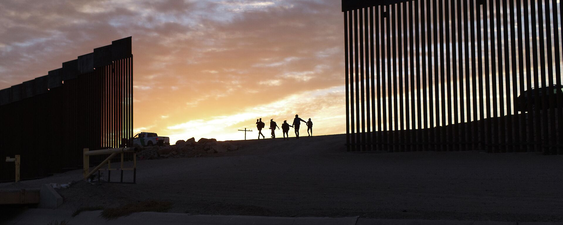 In this Thursday, June 10, 2021, file photo, a pair of migrant families from Brazil pass through a gap in the border wall to reach the United States after crossing from Mexico to Yuma, Ariz., to seek asylum. - Sputnik International, 1920, 01.04.2022