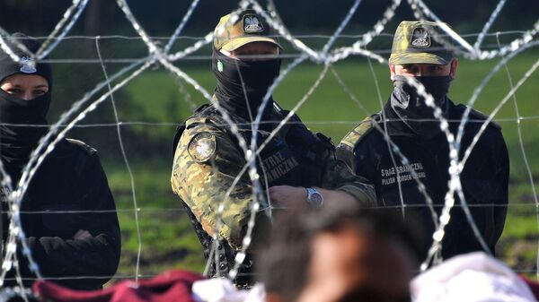 Polish border guards watch a refugee camp behind barbed wire installed on the border between Belarus and Poland near the village of Usnarz Dolny, Belarus - Sputnik International