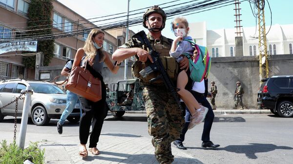 An army soldier carries a schoolchild as civilians flee after gunfire erupted at a site near a protest that was getting underway against Judge Tarek Bitar, who is investigating last year's port explosion, in Beirut, Lebanon October 14, 2021 - Sputnik International