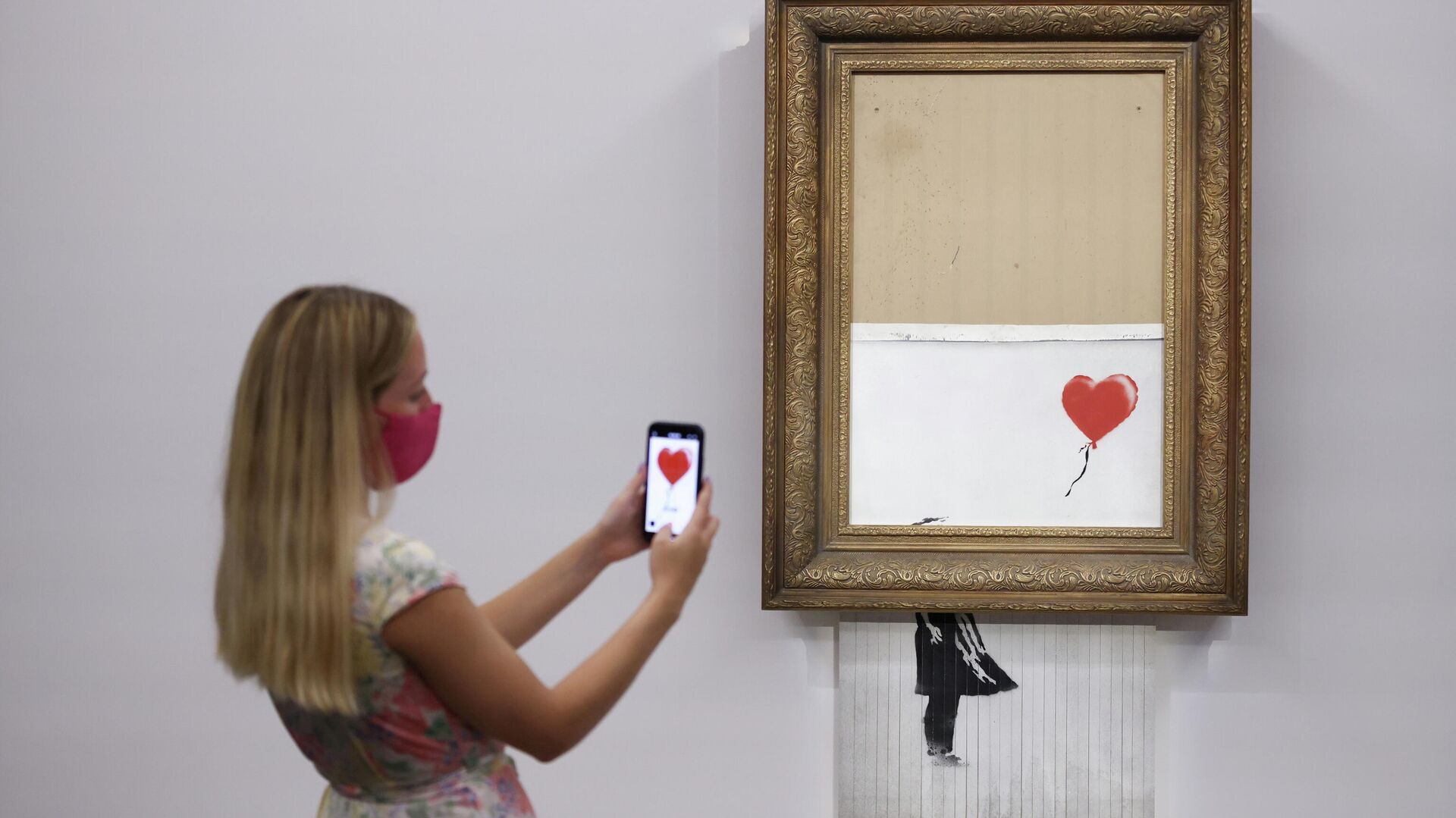FILE PHOTO: A gallery assistant poses by 'Love is in the Bin', an artwork by Banksy, which will be for sale in an auction, at Sotheby's in London, Britain, September 3, 2021.  - Sputnik International, 1920, 15.10.2021