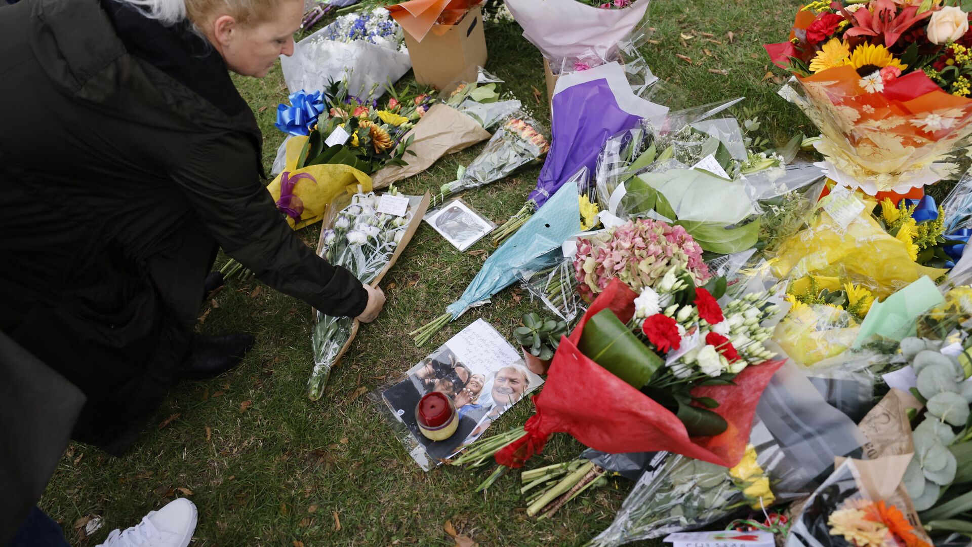 A member of the public adds a bunch of flowers to floral tributes left at the scene of the fatal stabbing of Conservative British lawmaker David Amess, at Belfairs Methodist Church in Leigh-on-Sea, a district of Southend-on-Sea, in southeast England on October 16, 2021. - Sputnik International, 1920, 16.10.2021
