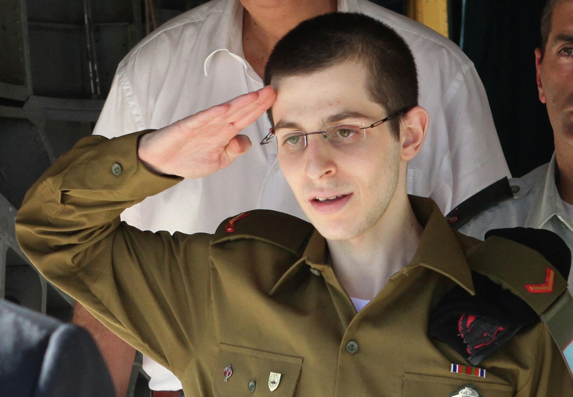 Israeli soldier Gilad Shalit saluting in front of Israeli Prime Minister Benjamin Netanyahu (unseen) as he arrives by helicopter at the Tel Nof airbase near Tel Aviv on 18 October 2011, following his release following 5 years of Hamas captivity under a landmark Egyptian-mediated deal that will see Israel release a total of 1,027 Palestinian prisoners.  - Sputnik International, 1920, 19.10.2021