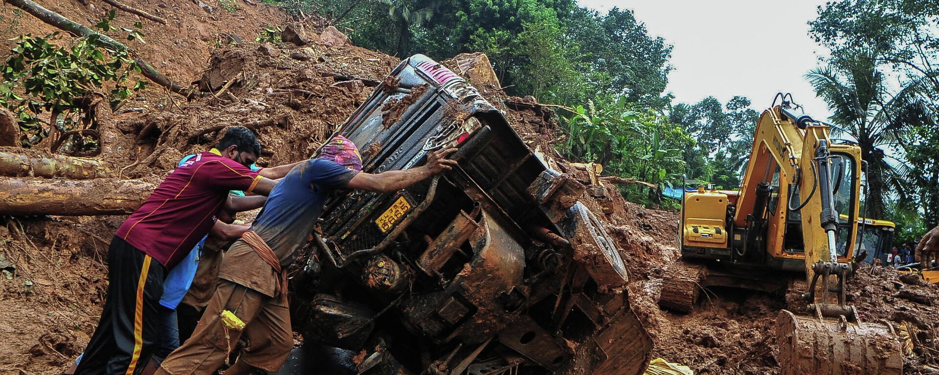 Rescue workers push a overturned vehicle stuck in the mud and debris at a site of a landslide claimed to be caused by heavy rains in Kokkayar in India's Kerala state on October 17, 2021 - Sputnik International, 1920, 18.10.2021