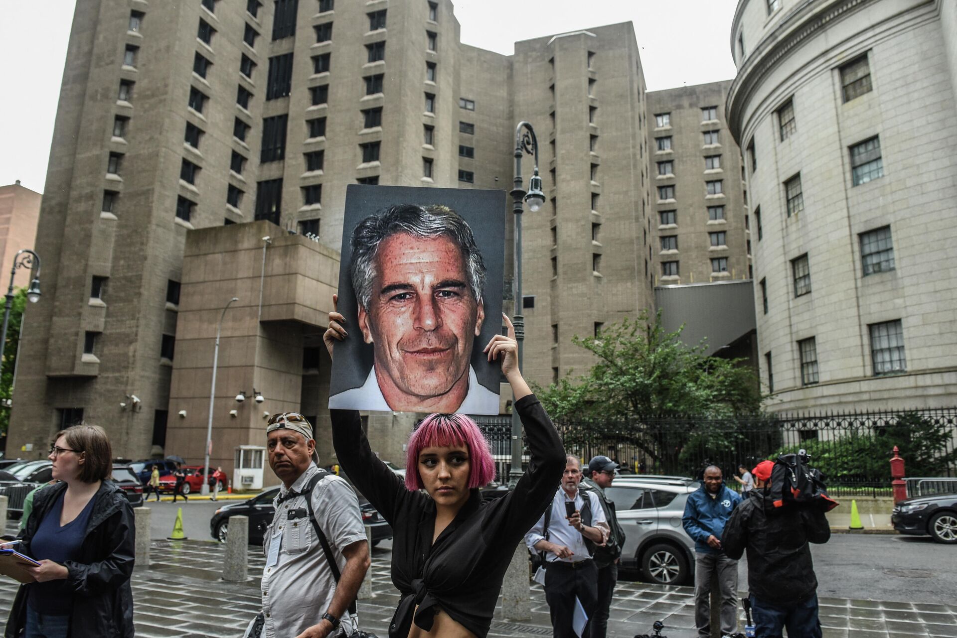 A member of a protest group called Hot Mess holds up a sign of Jeffrey Epstein in front of the Metropolitan Correction Center on July 8, 2019 in New York City. - Sputnik International, 1920, 01.11.2021