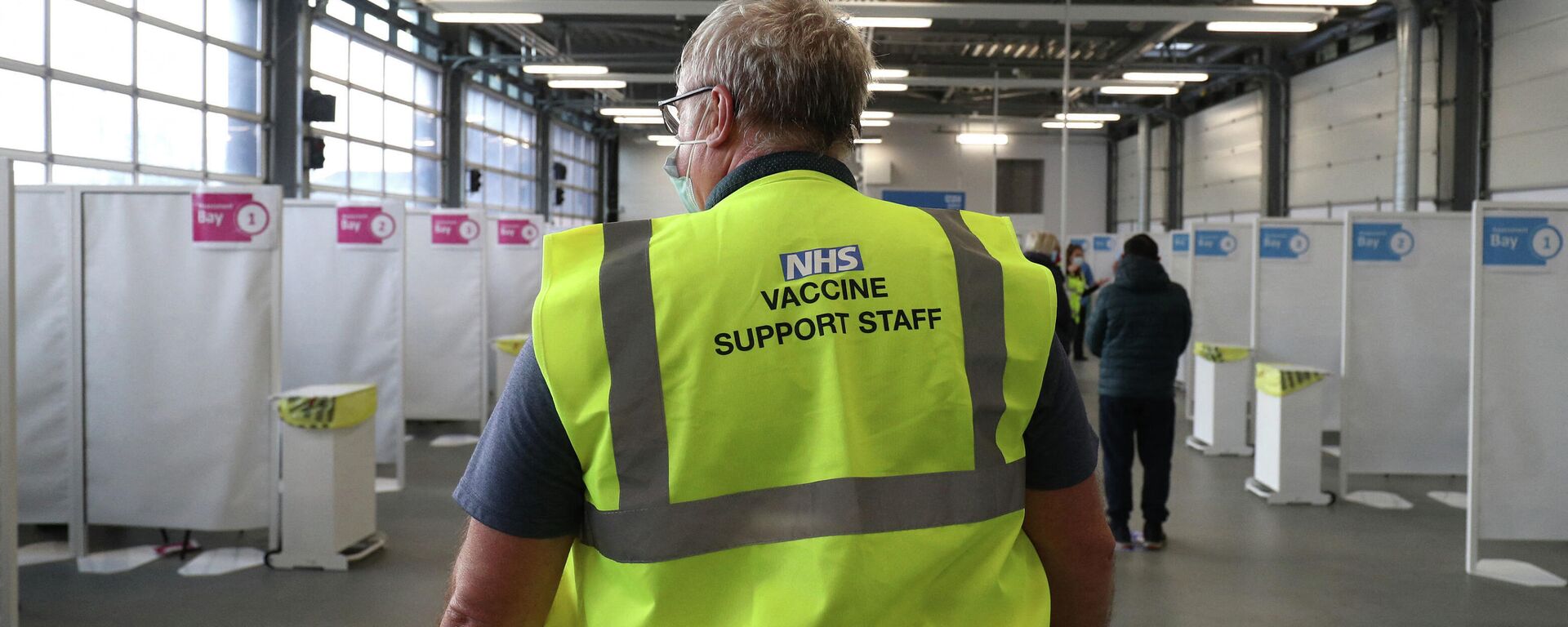 A member of the NHS vaccine support staff looks on as residents wait to receive the Oxford/AstraZeneca Covid-19 vaccine from a member of the Hampshire Fire and Rescue Service at a temporary vaccination centre set up at Basingstoke Fire Station, Hampshire, south England, as crews continue to take 999 emergency calls - Sputnik International, 1920, 20.10.2021