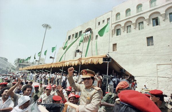 Gaddafi gives a clenched fist salute from his car as he leaves Tripoli&#x27;s Green Square on 1 September 1987. - Sputnik International