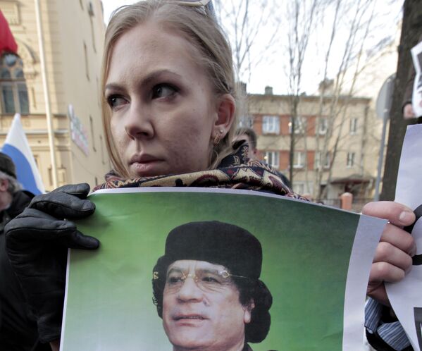 A woman holds Gaddafi&#x27;s portrait during a rally against foreign intervention in Libya in front of the US Consulate General in Saint Petersburg, March 2011. - Sputnik International