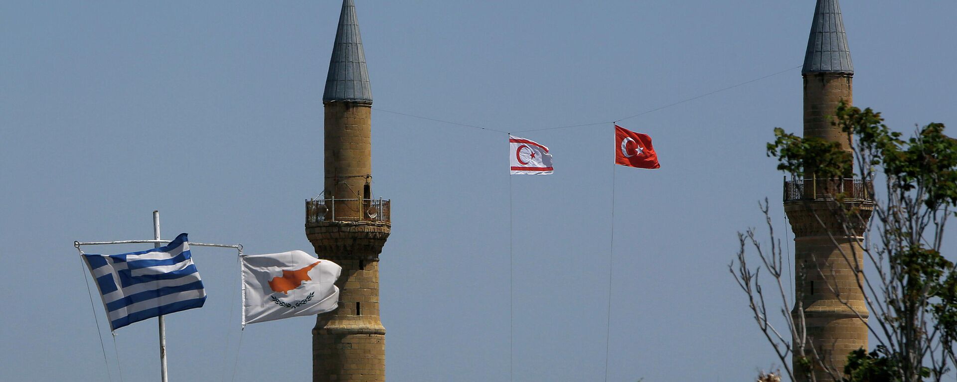 Greek, left, and Cyprus' flags, second left, flutter on poles in the south, as in the north Turkish occupied area, a Turkish and Turkish Cypriot breakaway flags fly on a minaret of the Selimiye mosque, or Cathedral of St Sophia, or Agia Sofia, in divided capital Nicosia, Cyprus, Monday, April 26, 2021 - Sputnik International, 1920, 21.02.2023
