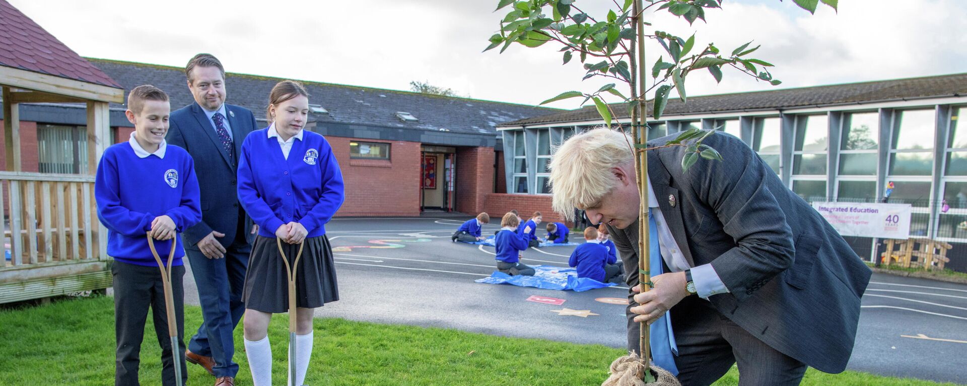 Britain's Prime Minister Boris Johnson plants a tree during a visit to Crumlin Integrated Primary School in County Antrim - Sputnik International, 1920, 25.10.2021