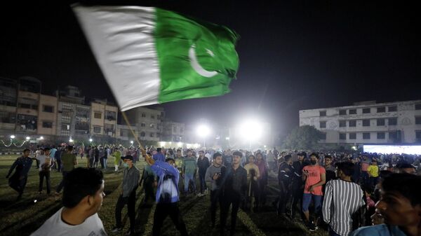A Pakistani cricket fan waves the national flag as fans celebrate the victory of the Pakistan cricket team on their first match between India and Pakistan in Twenty20 World Cup Super 12 stage in Dubai, at a park in Karachi, Pakistan October 24, 2021 - Sputnik International