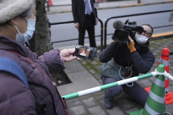 A passerby watches a mobile phone showing the press conference of former Princess Mako, niece of Emperor Naruhito, after they married without a traditional ceremony Tuesday 26 October 2021, in Tokyo. - Sputnik International