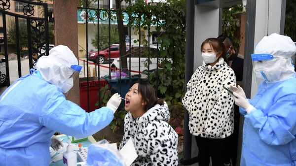 A medical worker in protective suit collects a swab from a resident at a free nucleic acid testing site following new cases of the coronavirus disease (COVID-19), in Lanzhou's Chengguan district, Gansu province, China October 20, 2021. - Sputnik International