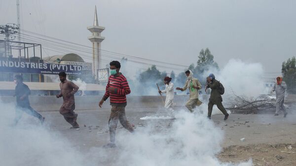 Supporters of the banned Islamist political party Tehrik-e-Labaik Pakistan (TLP) run amid the smoke of tear gas during a protest demanding the release of their leader and the expulsion of the French ambassador over cartoons depicting the Prophet Mohammed, in Lahore, Pakistan, October 23, 2021 - Sputnik International