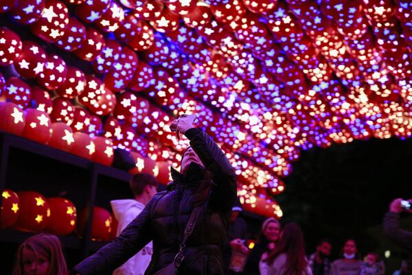 An attendee takes a picture under a canopy made of illuminated carved pumpkins during &quot;The Great Jack O’Lantern Blaze&quot; at Van Cortlandt Manor on 27 October 2021 in Croton-on-Hudson, New York, ahead of Halloween. - Sputnik International