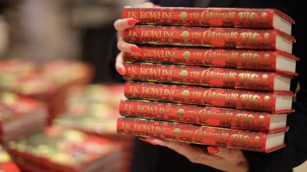 A shop worker poses with copies of The Christmas Pig, a children's book written by J. K. Rowling, at a Waterstones store in London, Britain, October 12, 2021. - Sputnik International