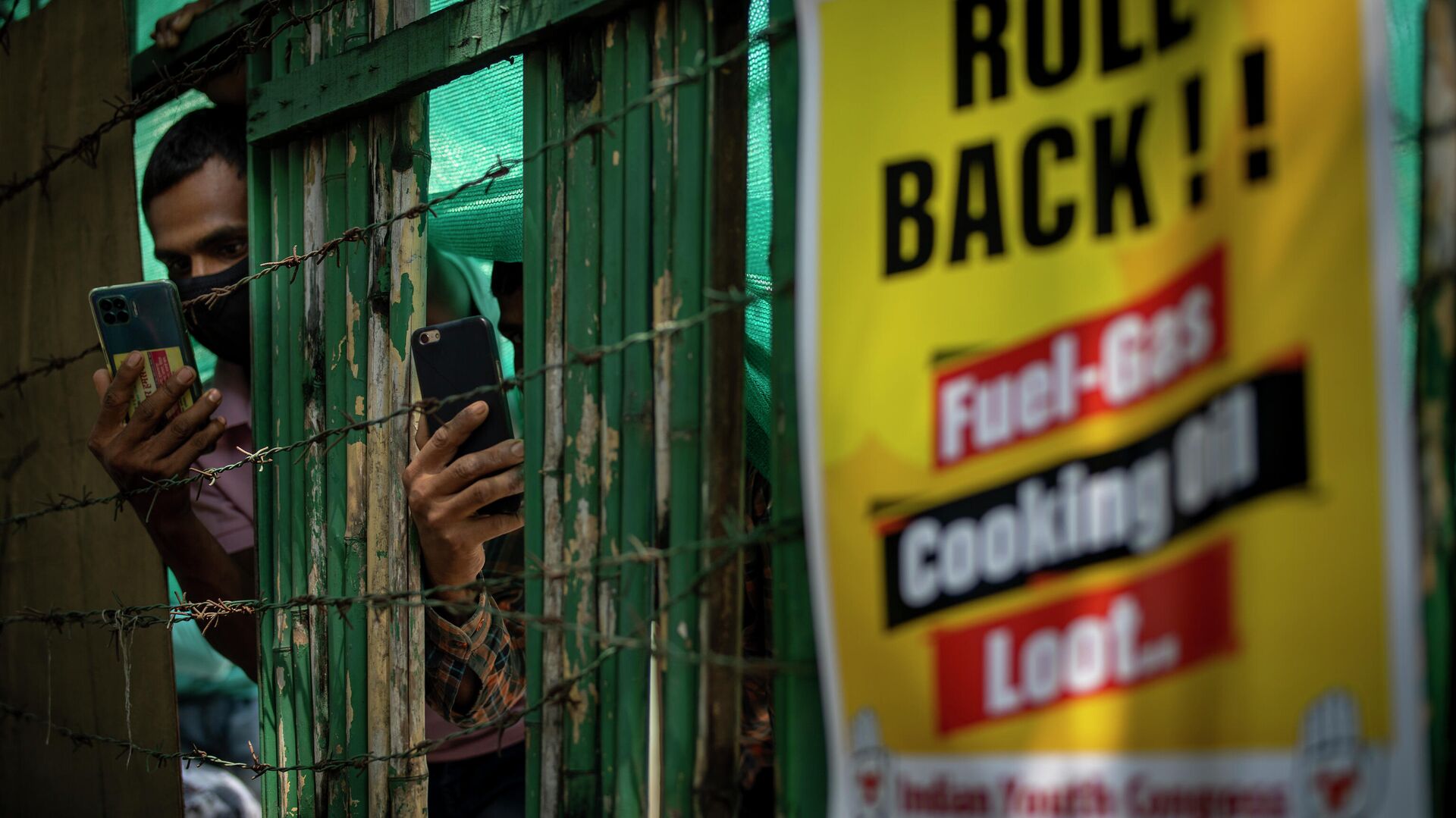 People take pictures through a fence as Congress party supporters protest against repeated hike of fuel and cooking gas prices in New Delhi, India, Thursday, Sept. 2, 2021. - Sputnik International, 1920, 31.10.2021